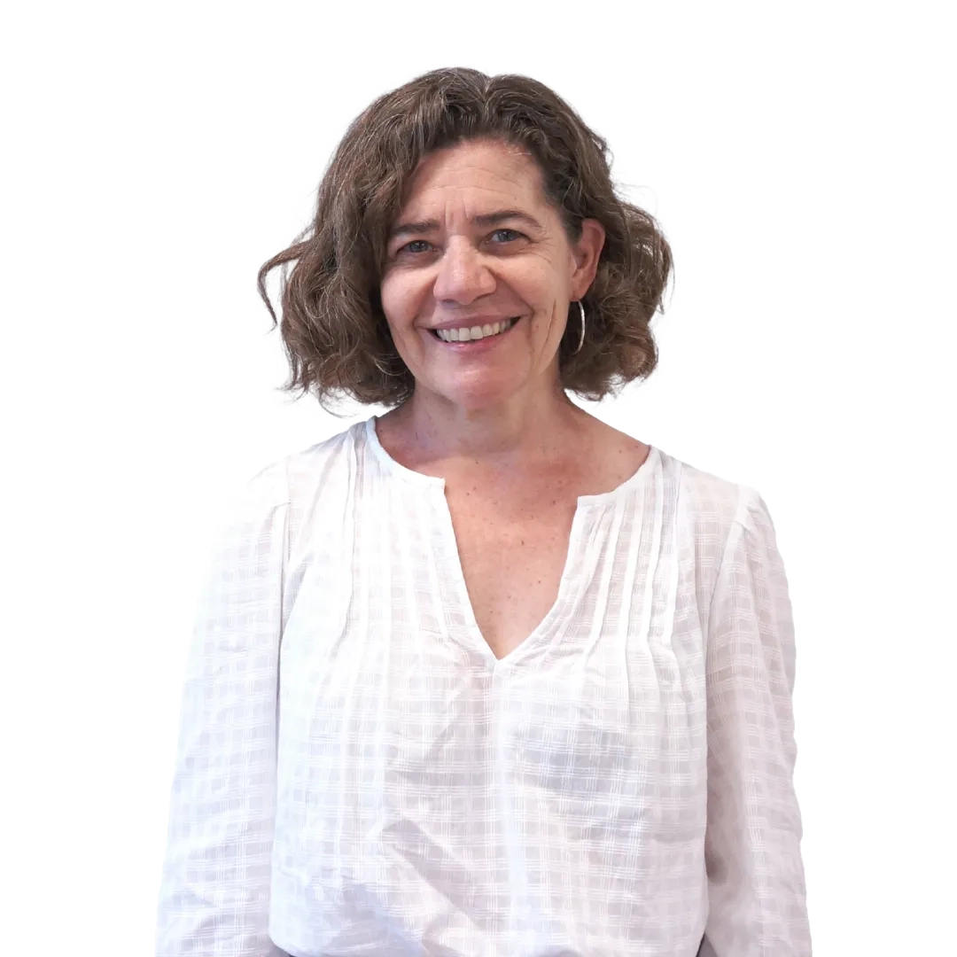 Retrato corporativo de Alejandra Grogg sonriendo, con blusa blanca de mangas largas sobre fondo blanco, en una pose profesional.