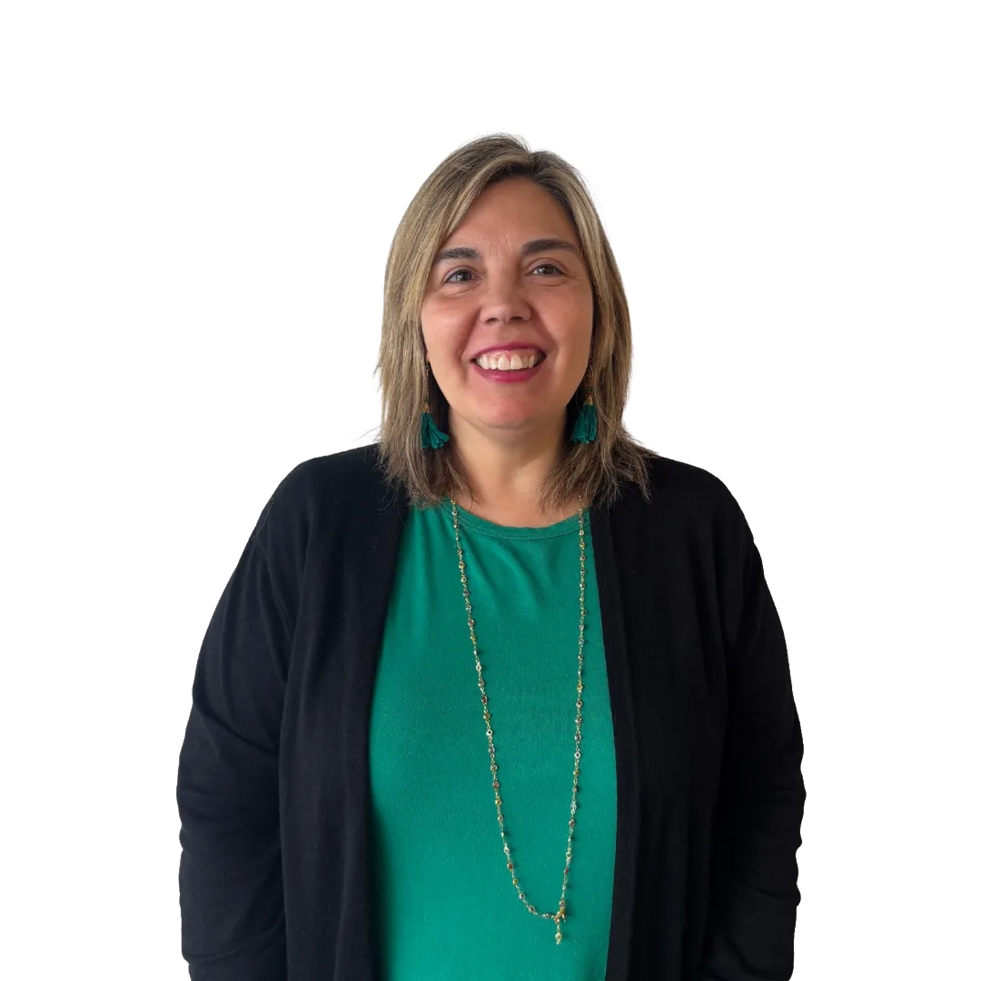Retrato corporativo de Carolina Sougarret sonriendo con cabello rubio a la altura de los hombros, blusa verde, cárdigan negro, collar largo y aros verdes, sobre un fondo blanco.