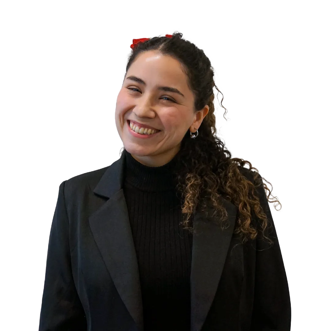 Retrato corporativo de Michelle Pinaud sonriendo, con blazer negro y sweater negro de cuello alto sobre fondo blanco, en una pose profesional.
