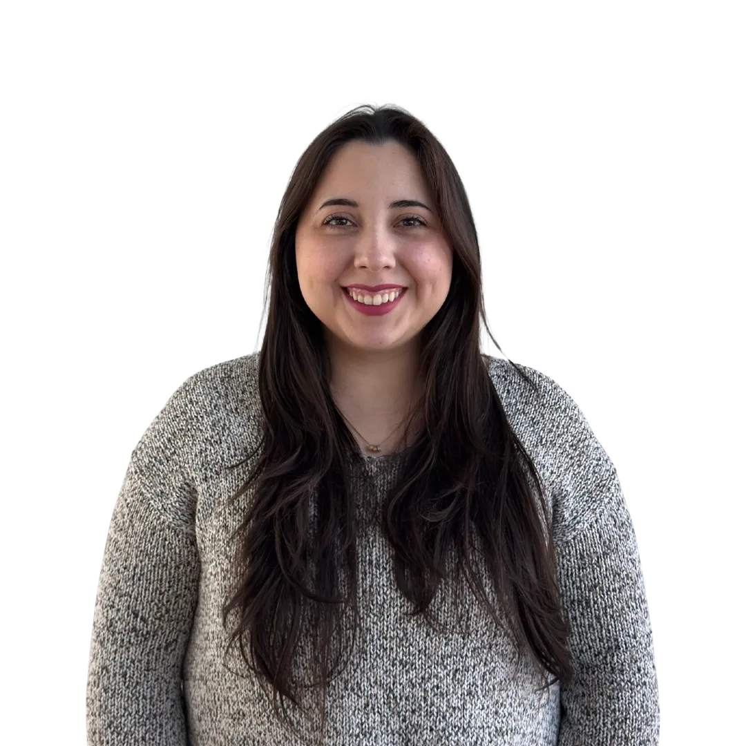 Retrato corporativo de Angela Martínez sonriendo, con sweater gris jaspeado sobre fondo blanco, en una pose cercana y profesional.