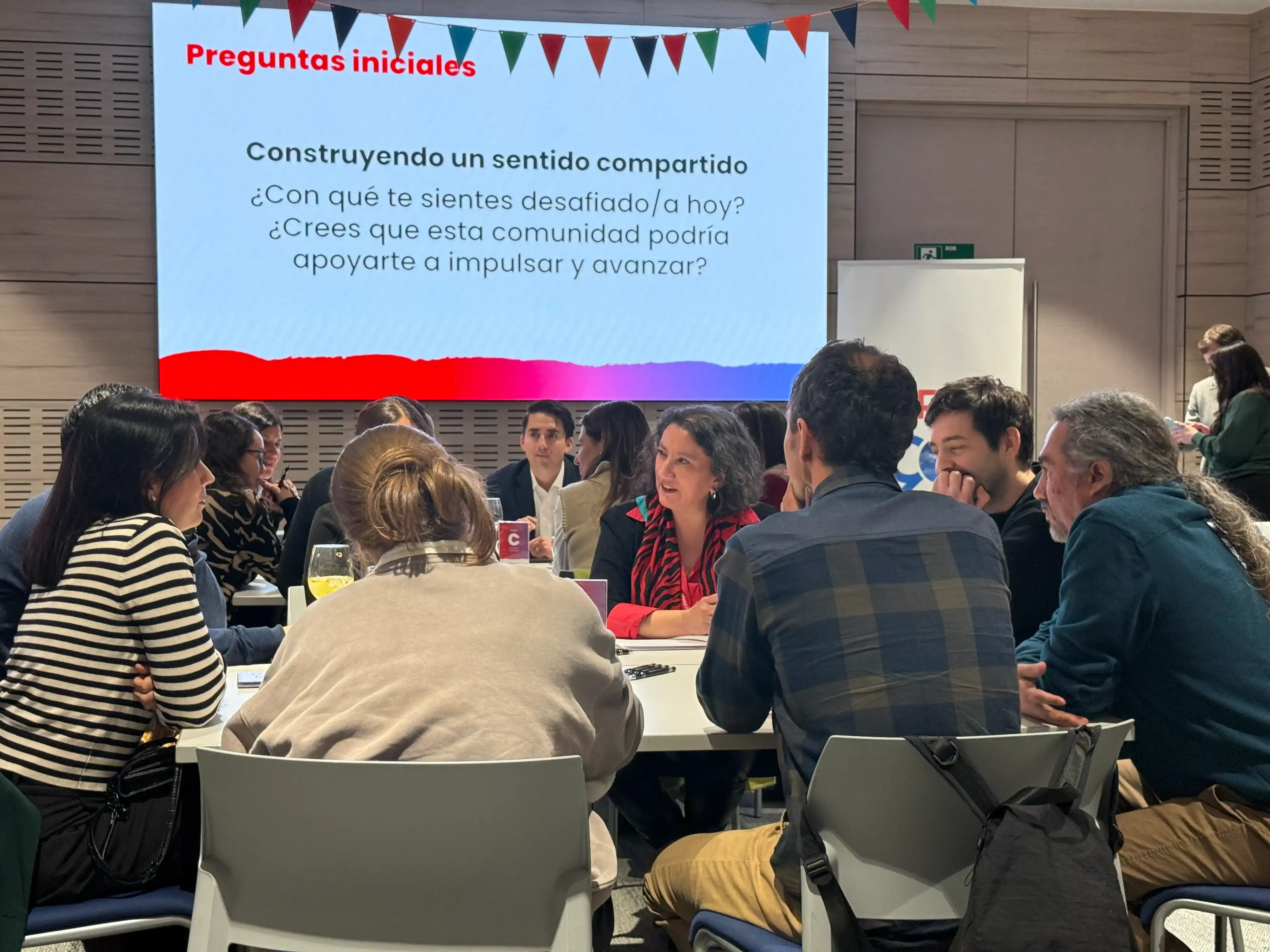 Participantes conversando en una mesa de trabajo durante una sesión de la Comunidad de Liderazgo con Propósito organizada por Almabrands.