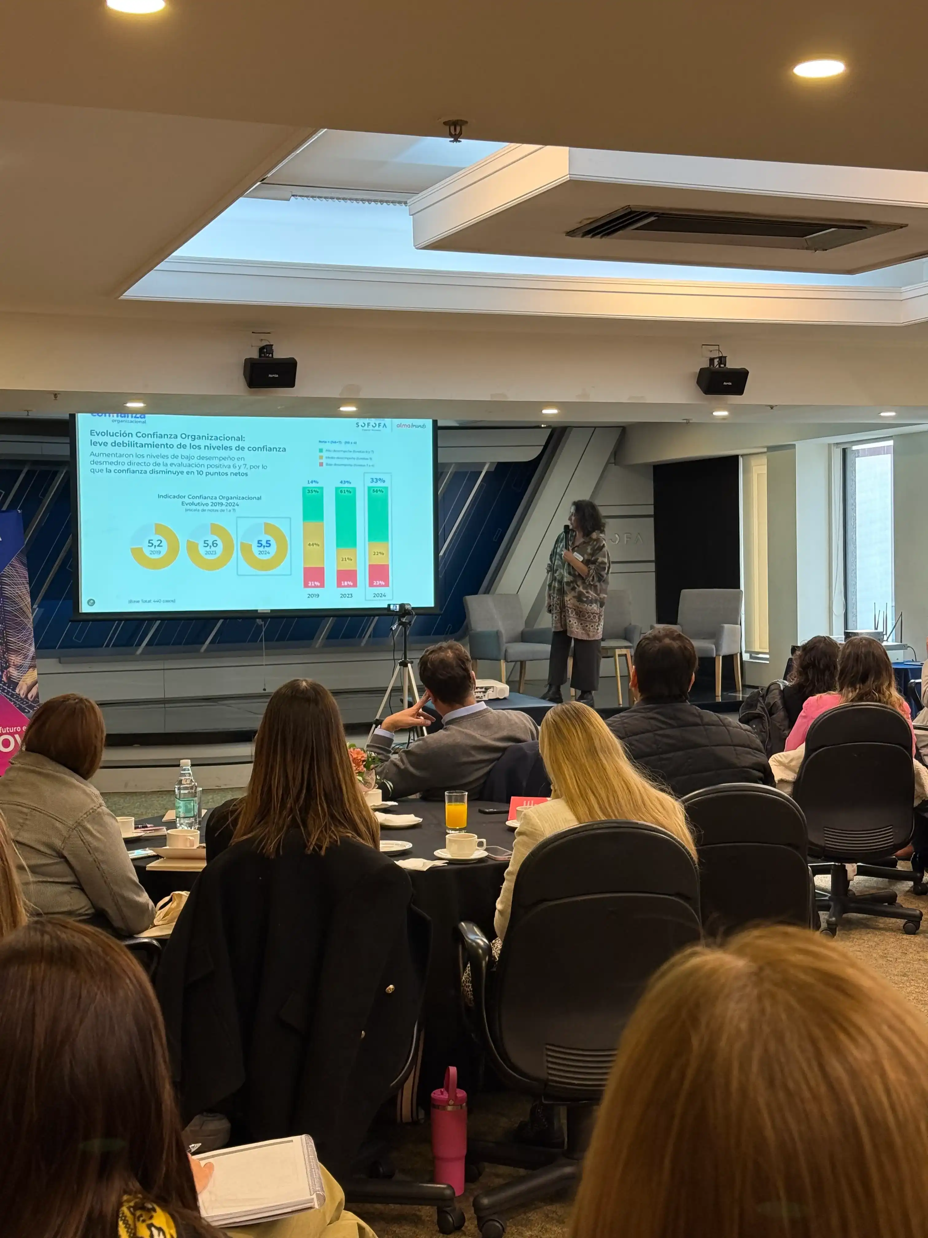 Pamela Ordenes presenta resultados y gráficos proyectados en pantalla frente a los asistentes del encuentro empresarial.