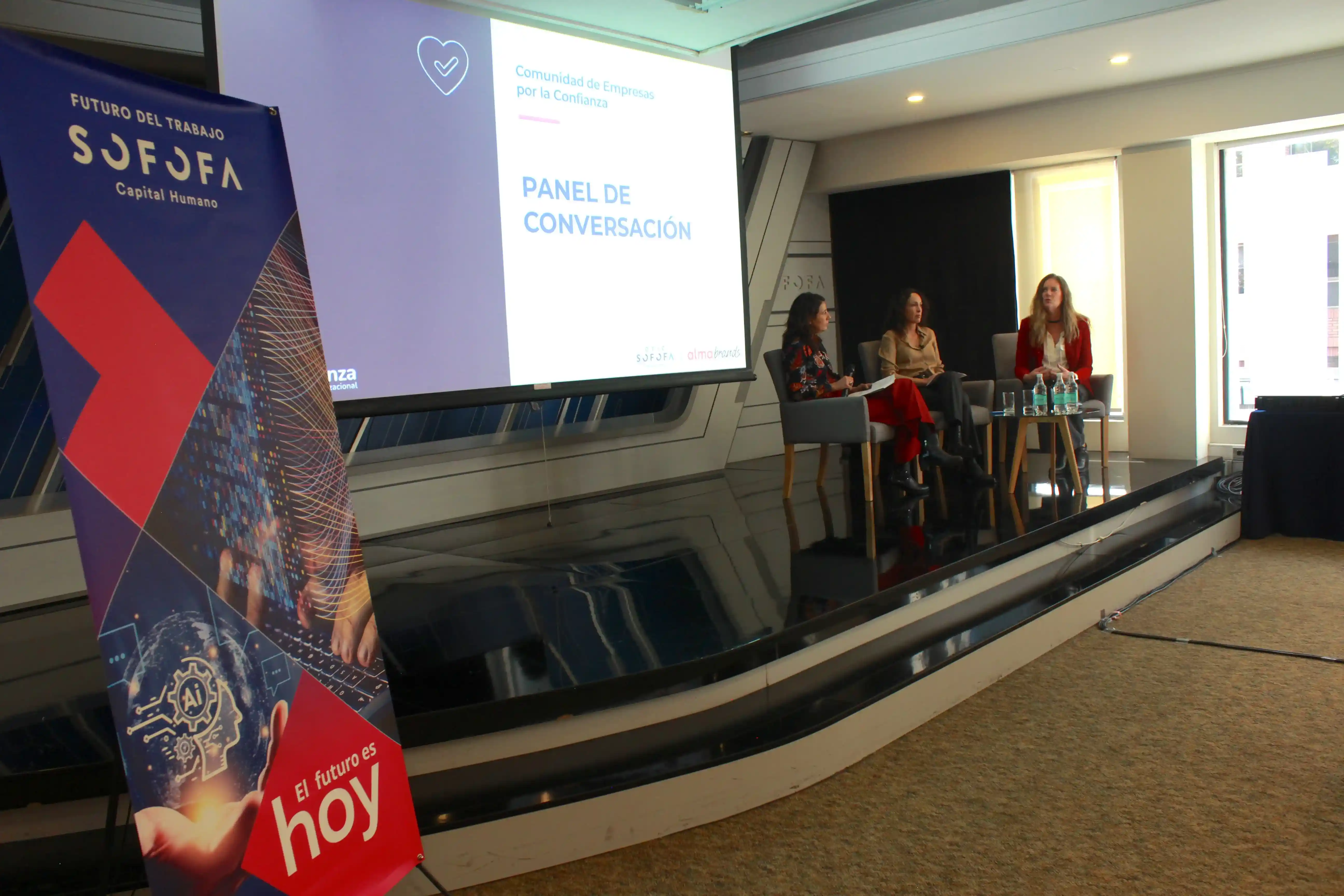 Tres panelistas participan en una conversación sobre confianza organizacional frente a una audiencia reunida en el auditorio.