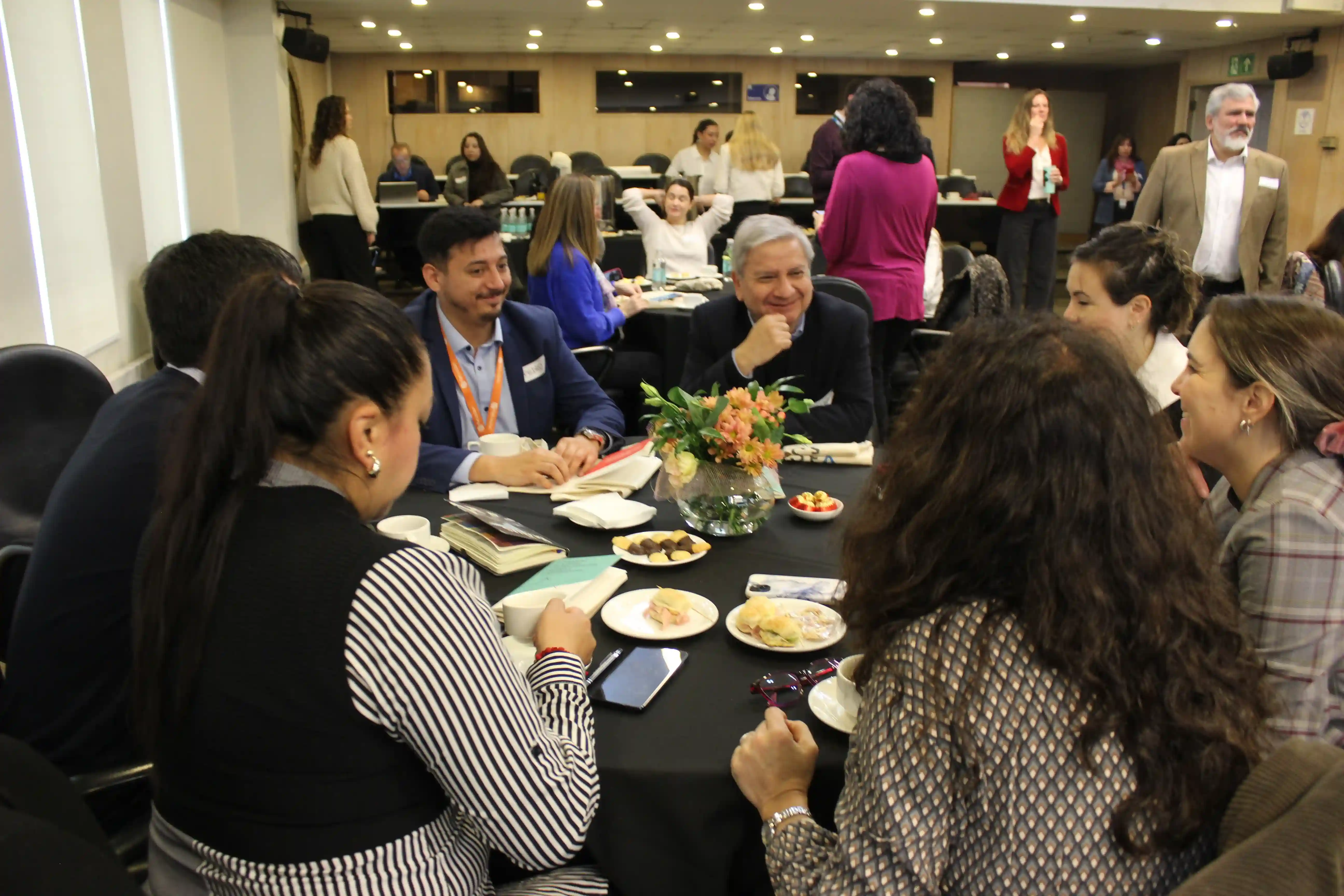 Grupo de asistentes conversa y comparte experiencias en una mesa de trabajo colaborativo durante el encuentro empresarial.