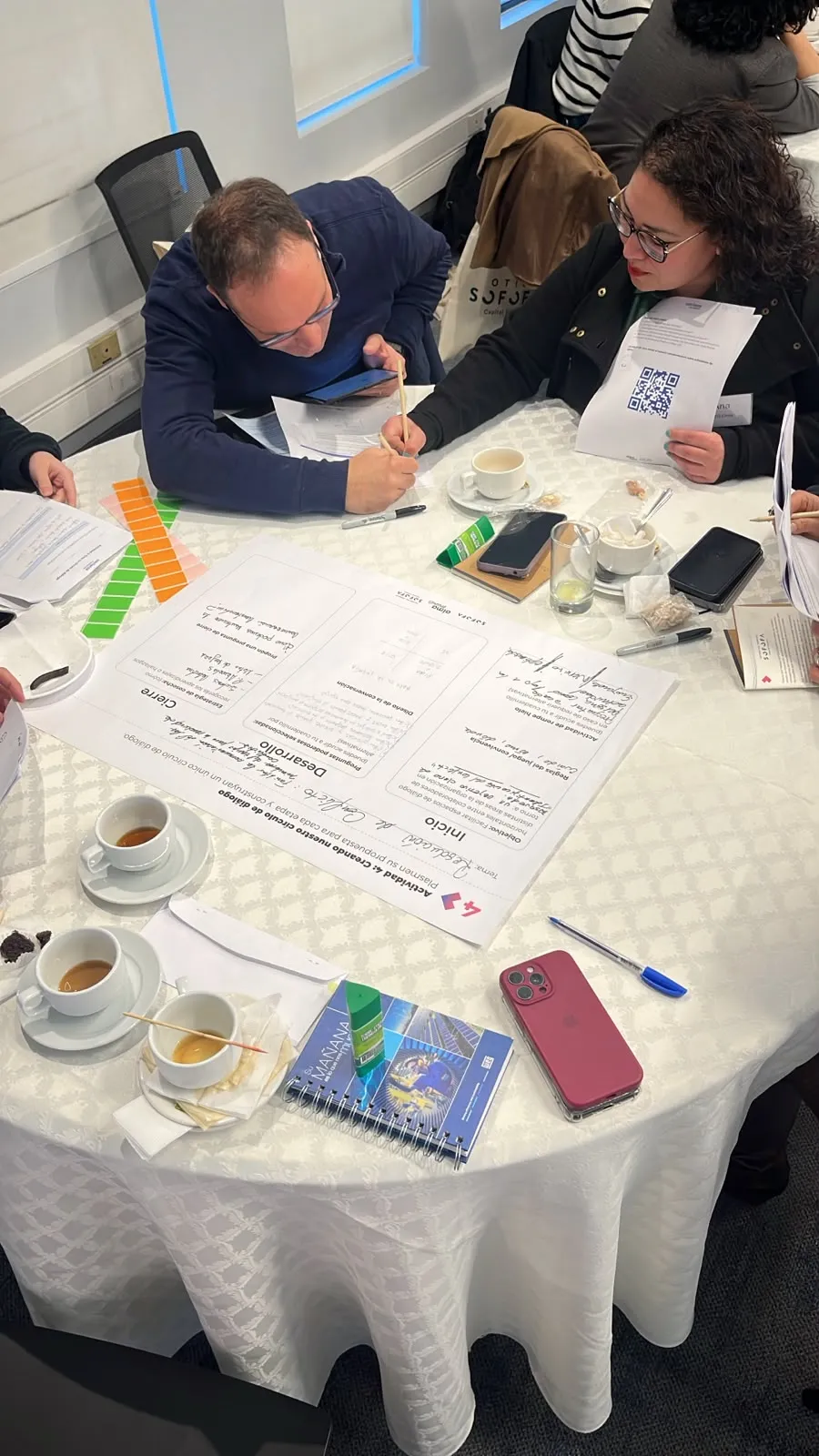 Participantes completan una guía de trabajo y escriben respuestas durante una actividad colaborativa realizada en mesas.