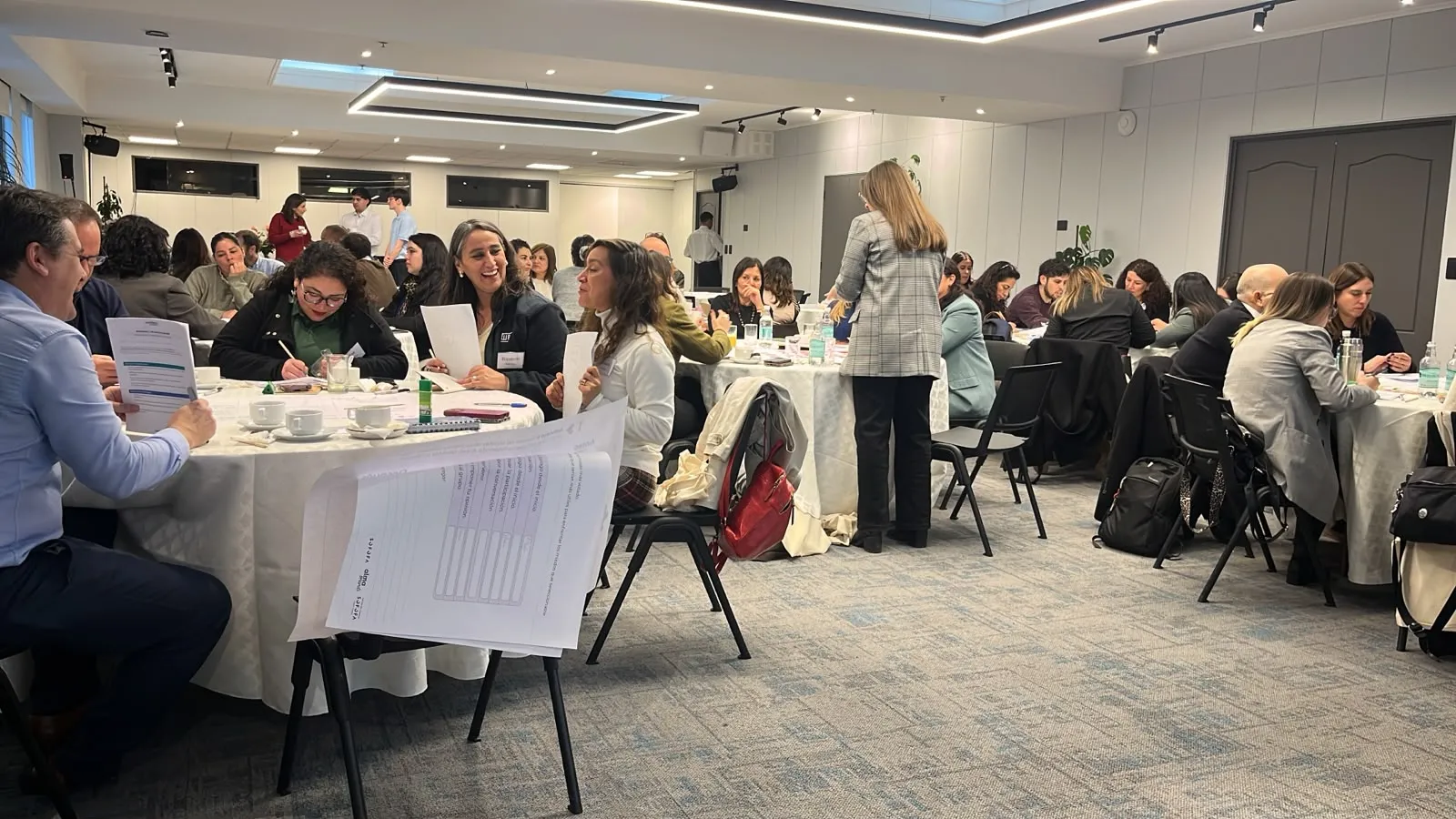 Equipos trabajan en mesas colaborativas revisando documentos y conversando durante el Segundo Encuentro de la Comunidad por la Confianza.
